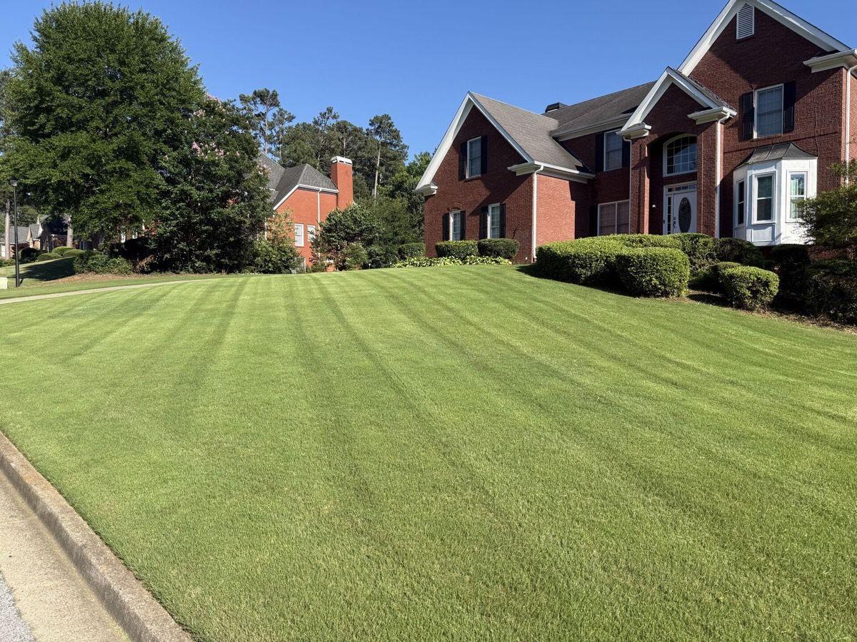 Thick, even striped lawn in front of a brick Newton County home by Kaus Cuts