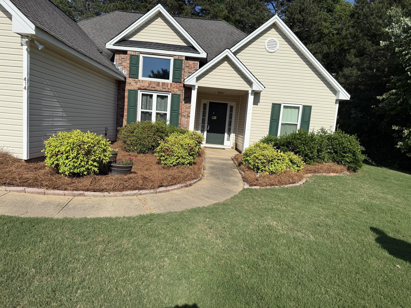 Home with a freshly trimmed lawn and shrubs maintained by Kaus Cuts