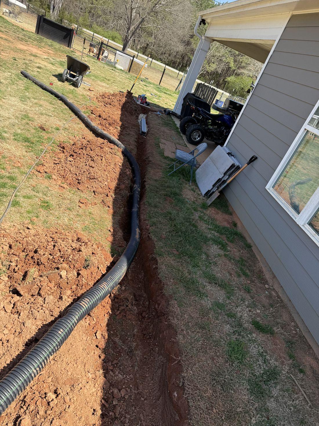 Irrigation and drainage line work along a foundation by Kaus Cuts
