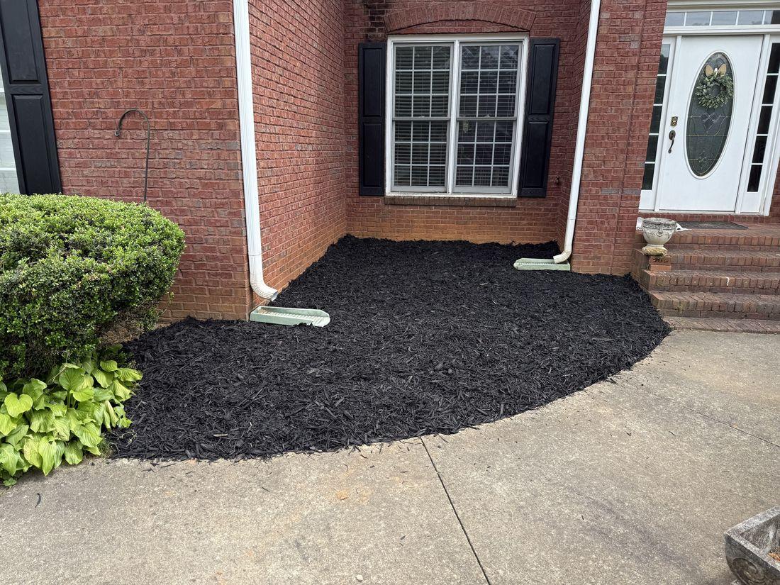 Fresh dark mulch bed along a brick home entry by Kaus Cuts